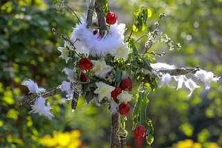 Osterkreuz mit Blumen und Federn geschmückt