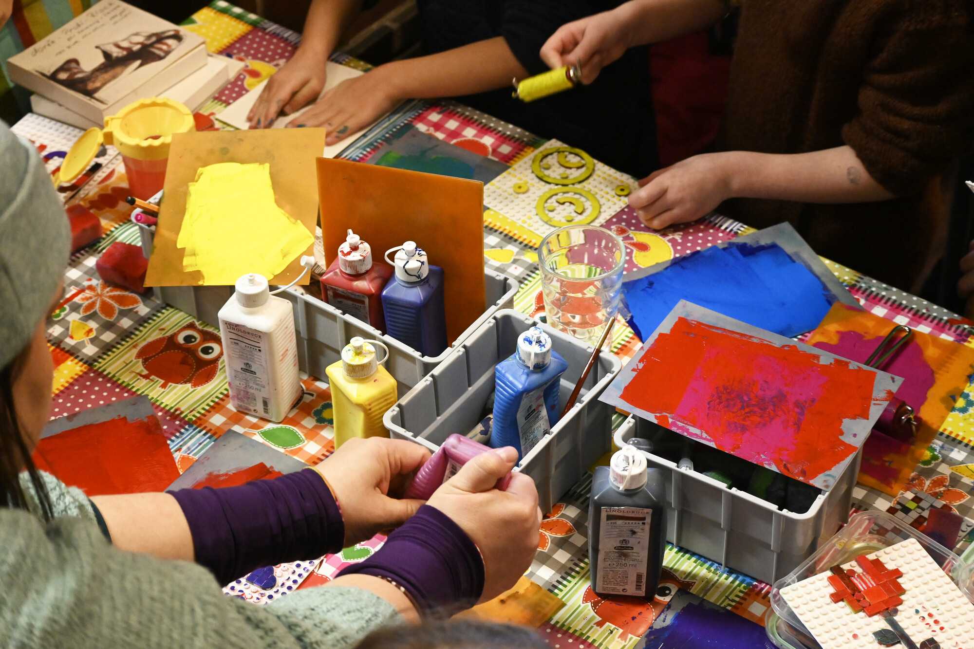 Auf einem Tisch stehen einige Flaschen mit Bastelfarbe. Einige Kinder basteln und spielen mit den Farben. (Foto: Katharina Pfuhl / fundus-medien.de)